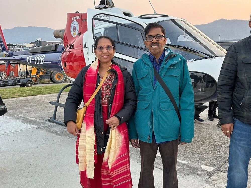 Guest couple beside a Himalayan Heli Services helicopter at golden hour